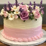 A pastel-colored flower crown cake decorated with soft pink, lavender, and white flowers.