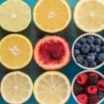 A refreshing assortment of fruit slices, including lemon, strawberries, and oranges, next to glasses of freshly made fruit lemonade.