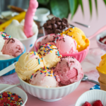 Bright scoops of homemade ice cream in colorful bowls, topped with rainbow sprinkles and served with small spoons.